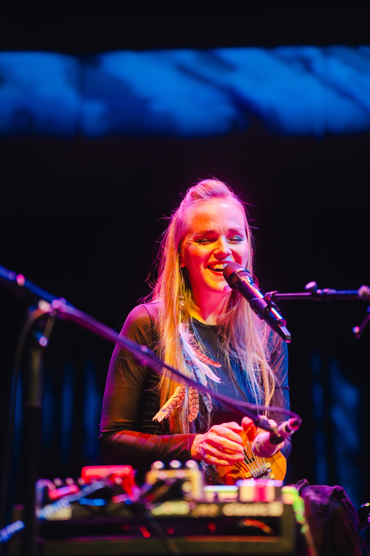 Kadri Voorand singing into a microphone under blue stage light.