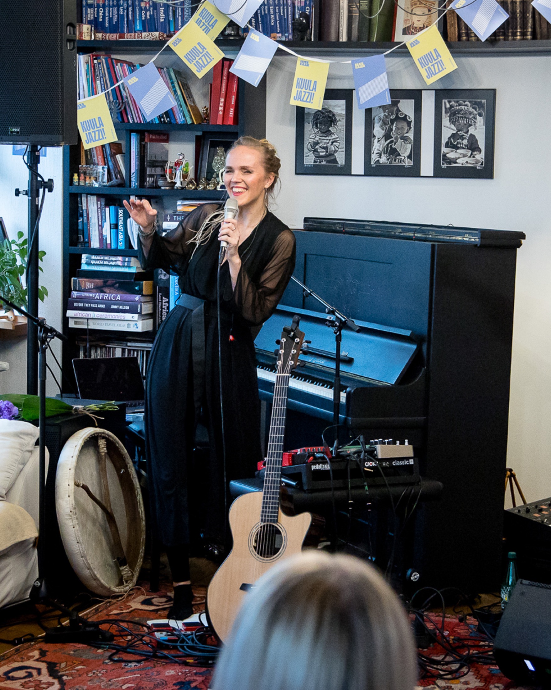 Kadri Voorand performing in an intimate room with guitar and piano.